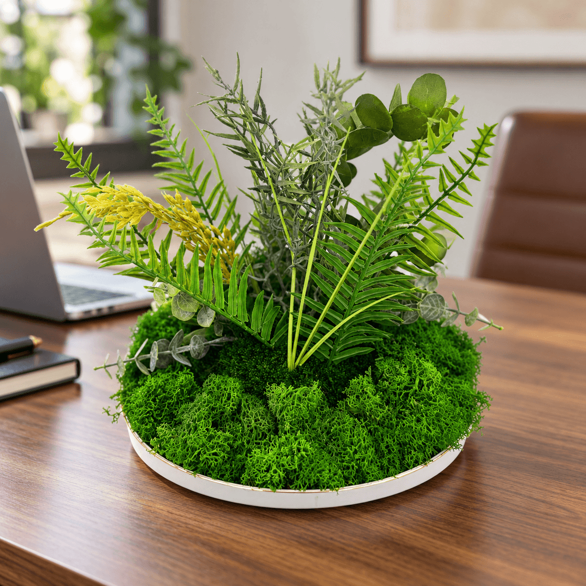Decorațiune cu licheni și plante artificiale pe un birou din lemn, lângă un laptop