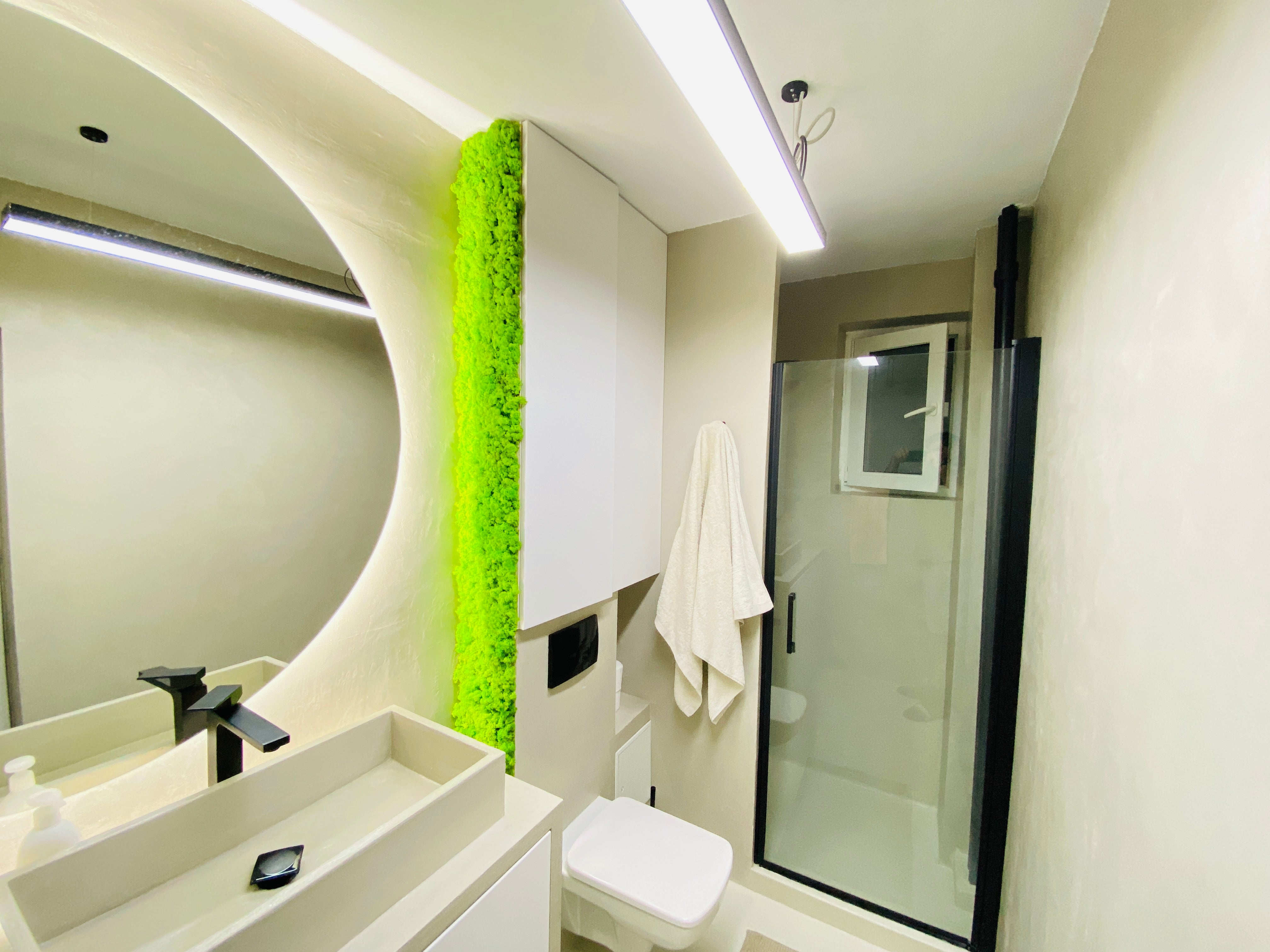 Panou decorativ vertical cu licheni stabilizați verde primăvară, montat într-o baie modernă cu design minimalist și iluminare subtilă.

