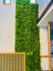 Perete decorativ vertical realizat din plante artificiale verzi, montat în interior