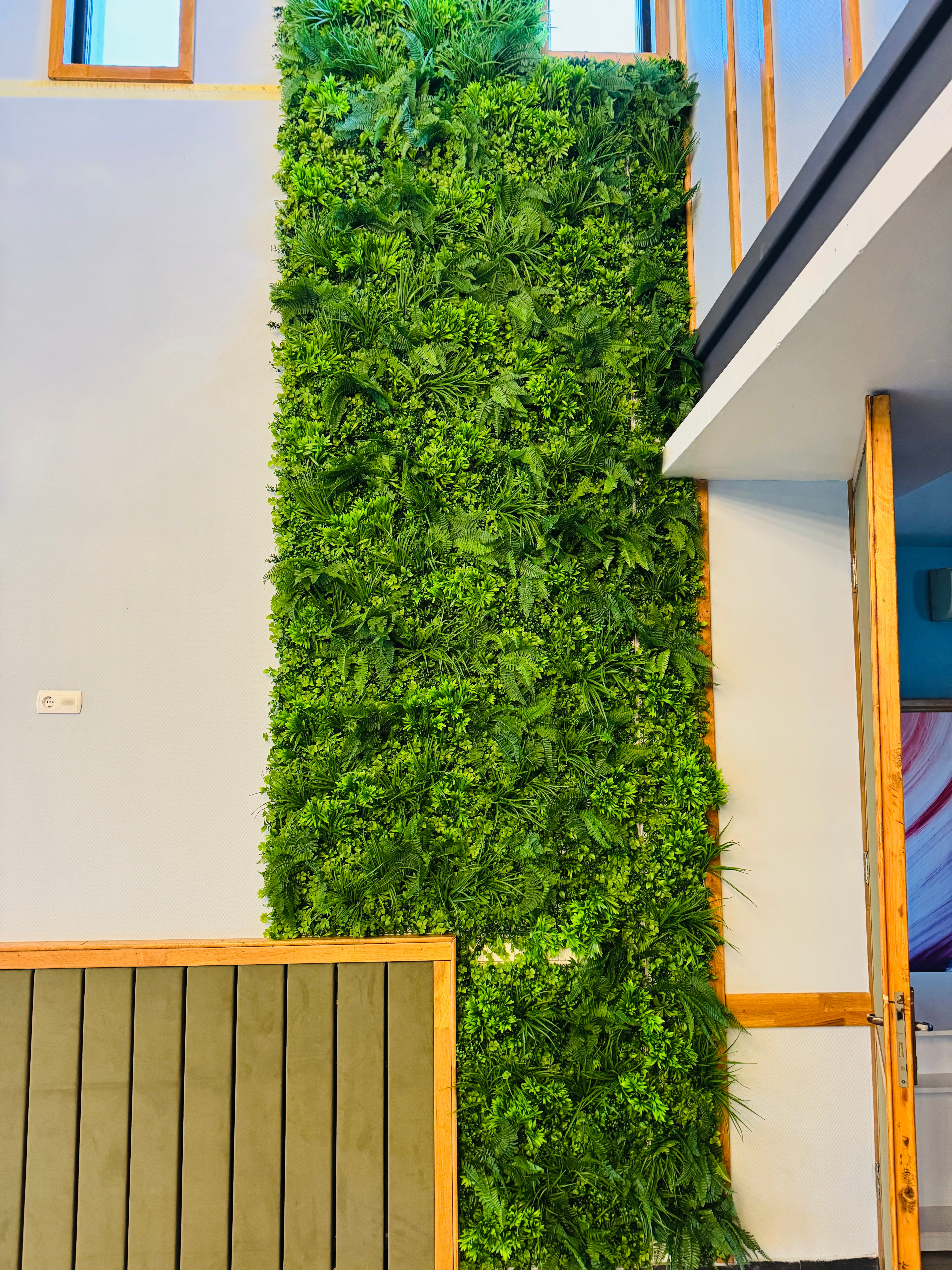 Perete decorativ vertical realizat din plante artificiale verzi, montat în interior
