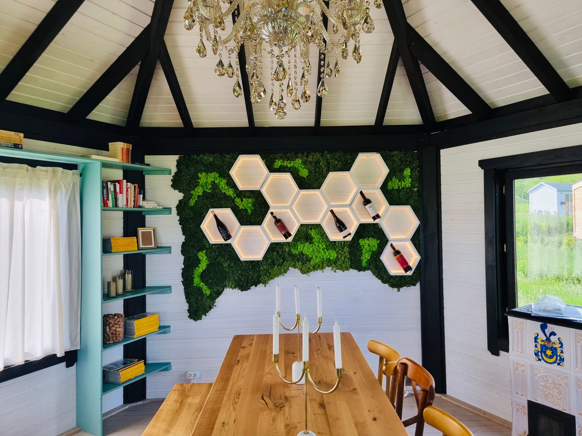 Compoziție cu rafturi hexagonale luminate montate pe perete decorat cu mușchi stabilizați, într-un dining cu tavan rustic